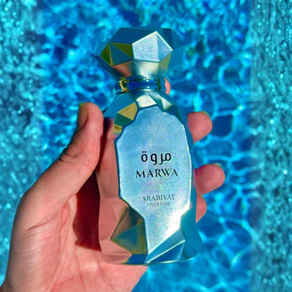 Arabiyat Prestige Marwa Eau de Parfum 100ml for Men bottle held over blue water
