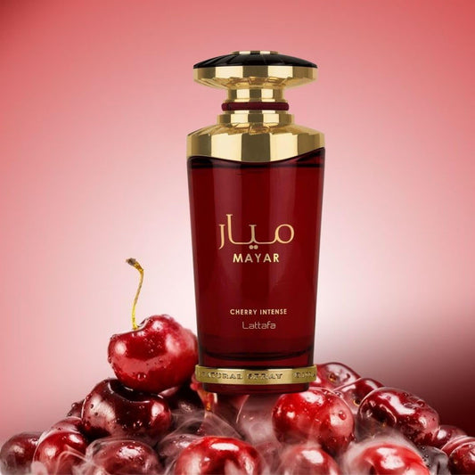 Red perfume bottle with gold accents on a pink background with cherries