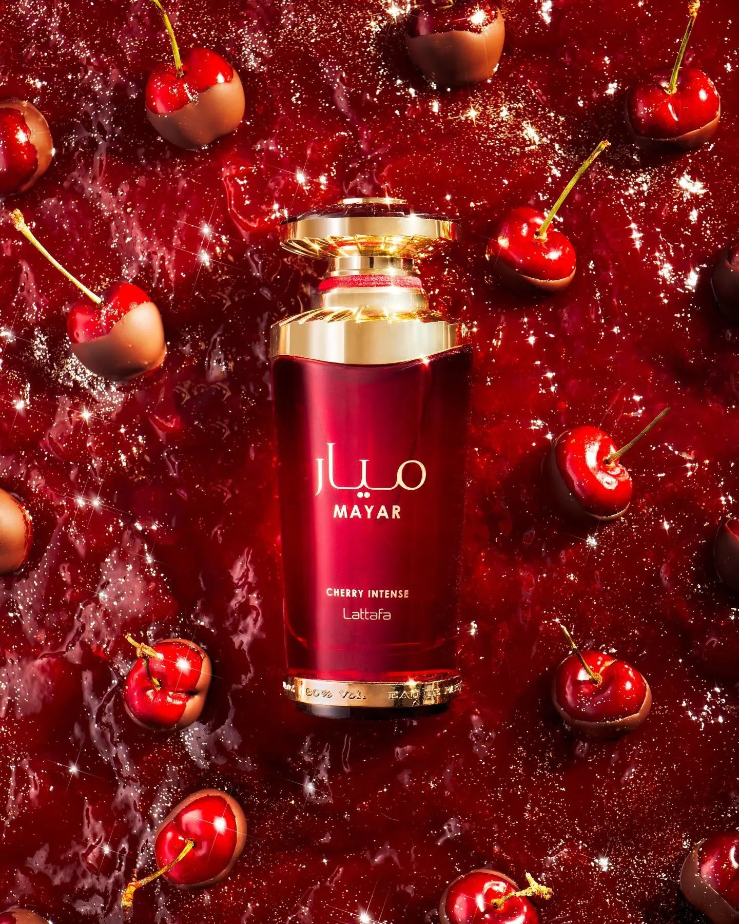 Red perfume bottle with gold accents surrounded by cherries on a red background