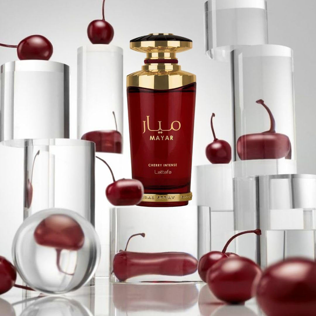 Red perfume bottle with gold cap labeled 'MAYAR' surrounded by cherries on a reflective surface.