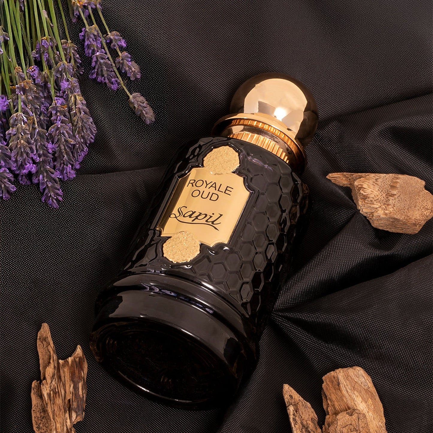 Sapil Royale Oud bottle lying on fabric with lavender and wood