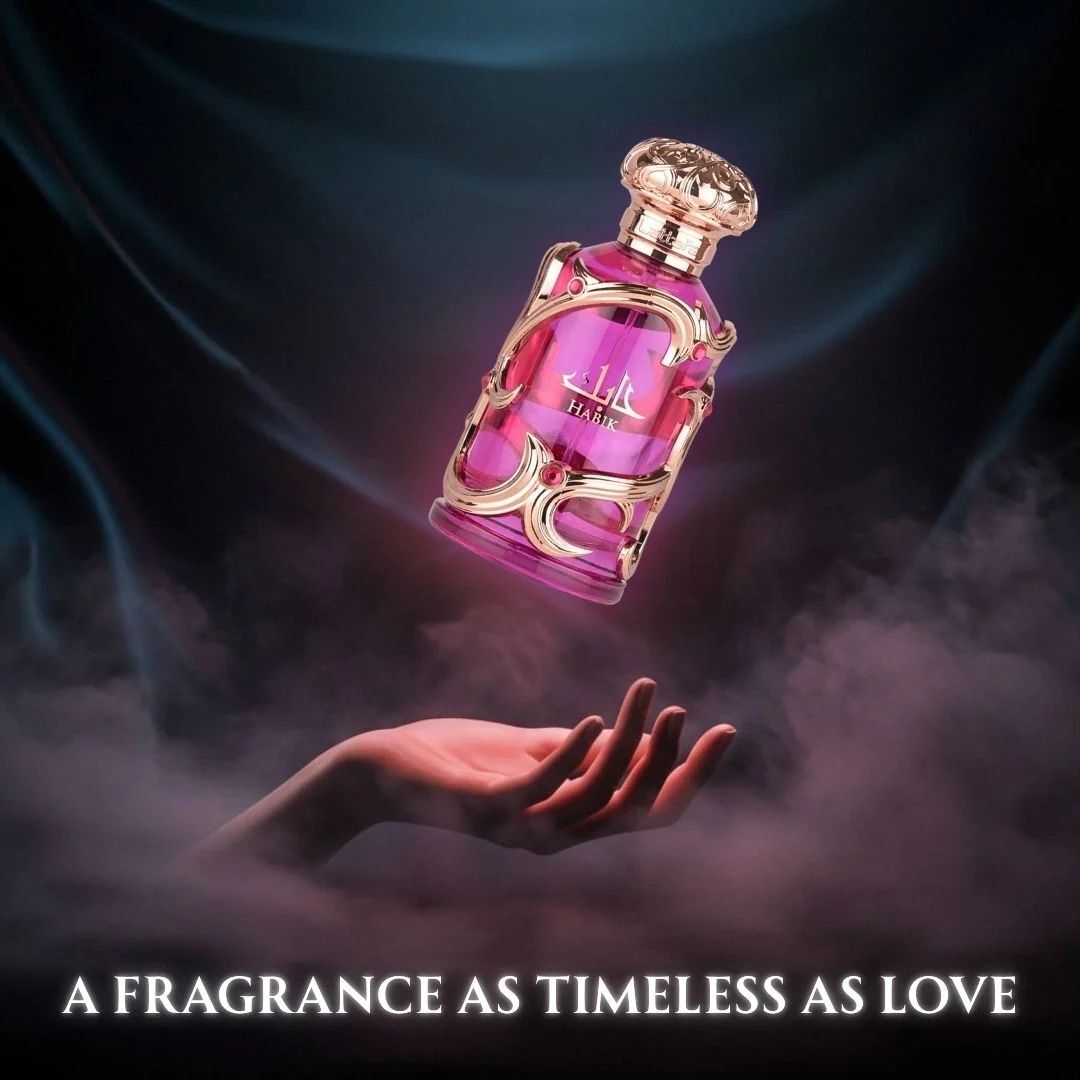 Habik luxury pink perfume bottle floating above a hand in a dramatic smoky background with the slogan “A fragrance as timeless as love,” highlighting an elegant romantic fragrance advertisement.