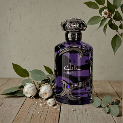 Lattafa Habik for Him men's perfume bottle in deep purple glass with silver ornate detailing displayed on a wooden surface with white flowers and green leaves, highlighting an elegant masculine fragrance.