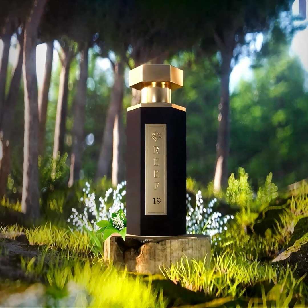 Reef 19 luxury perfume bottle displayed in a forest setting with lily of the valley flowers, highlighting fresh floral notes in an elegant Arabian fragrance.