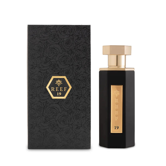 Reef 19 unisex eau de parfum 100ml in a matte black bottle with gold detailing, shown beside its matching black embossed box, styled in a clean luxury fragrance presentation.