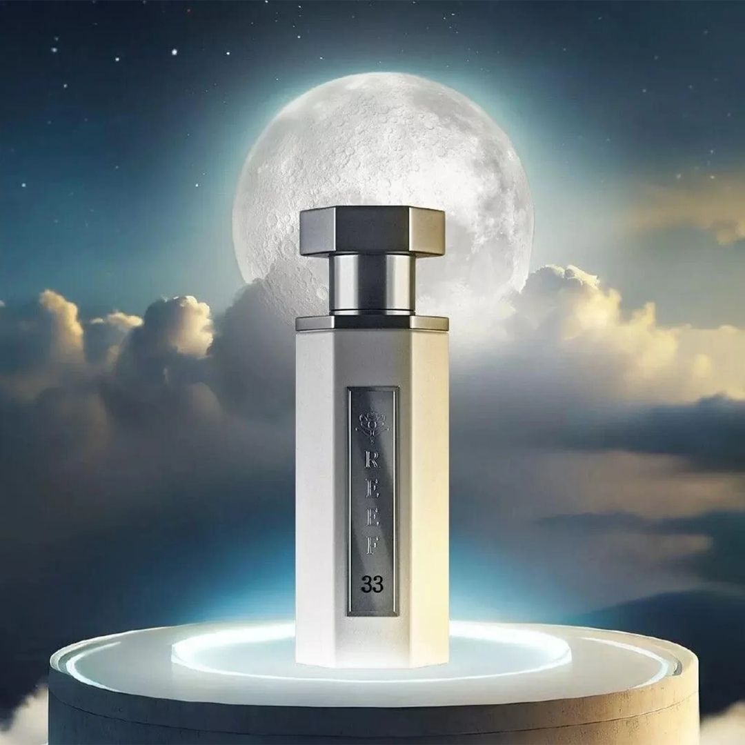 Reef 33 luxury white perfume bottle displayed on a glowing platform under a full moon and cloudy night sky, representing an elegant and mysterious fragrance concept.