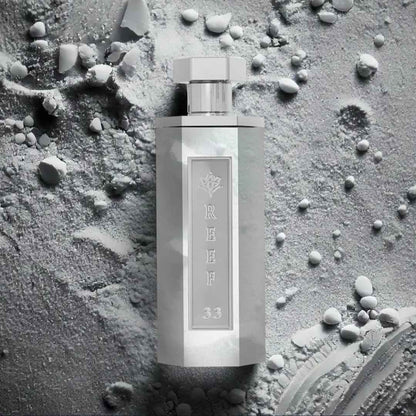 Reef 33 luxury white perfume bottle displayed on textured powder surface highlighting a clean, soft, and elegant fragrance concept.